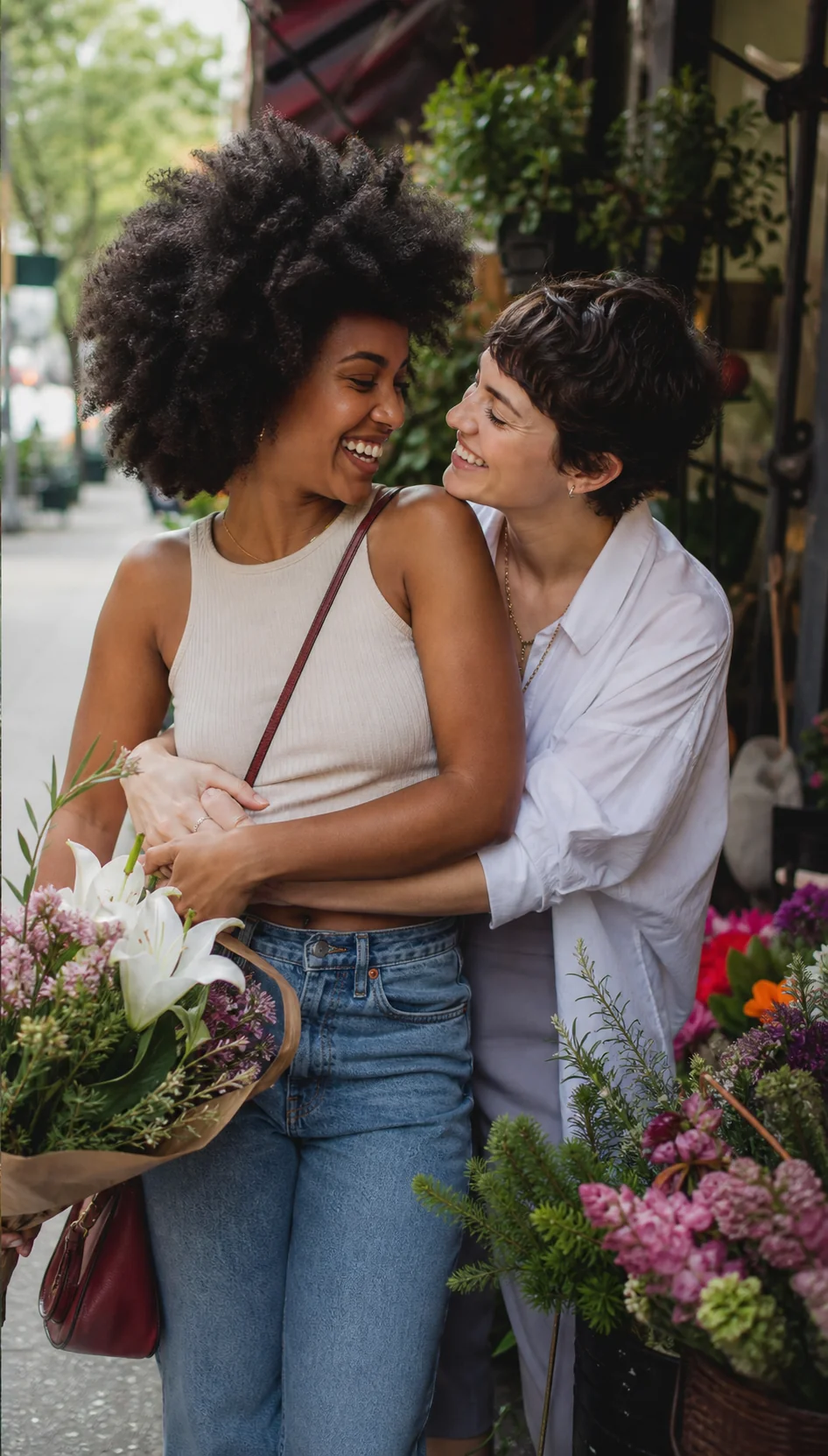 A lesbian couple laughing together by a flower shop